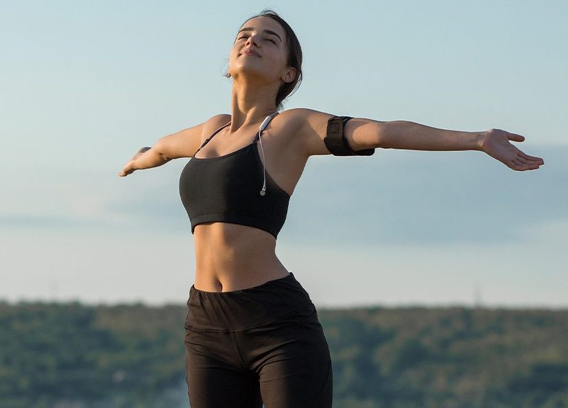 Photo of a woman on a jog in nature, extending her arms out