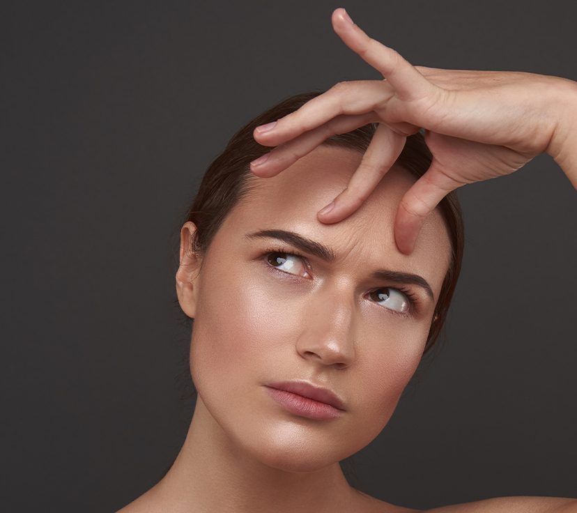 Photo of a woman touching her frown lines and forehead