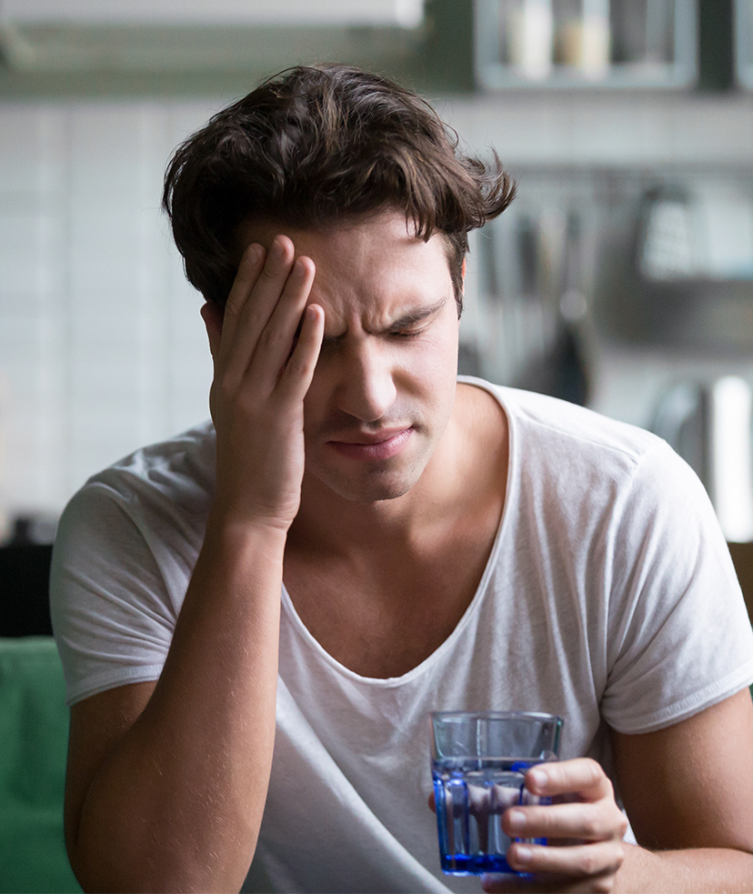 Photo of a man with a hangover holding a glass of water