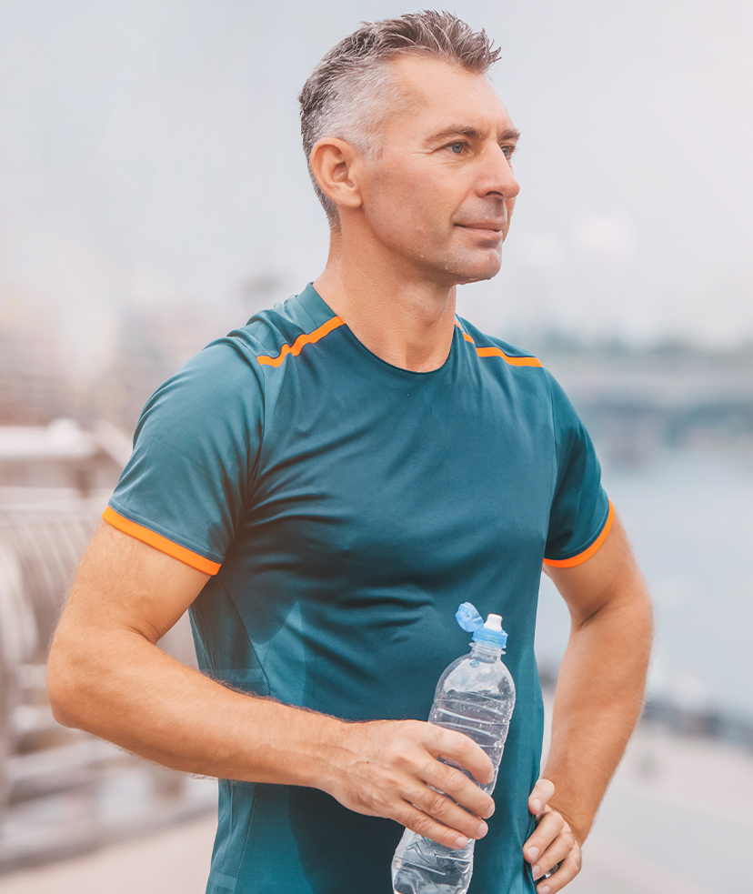 Photo of a sweaty man in workout clothes holding a bottle of water