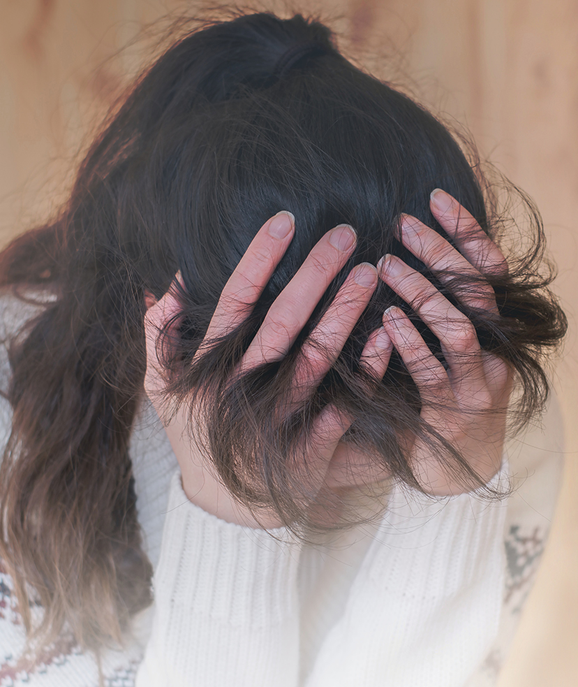 Photo of a distressed woman covering her face with her hands