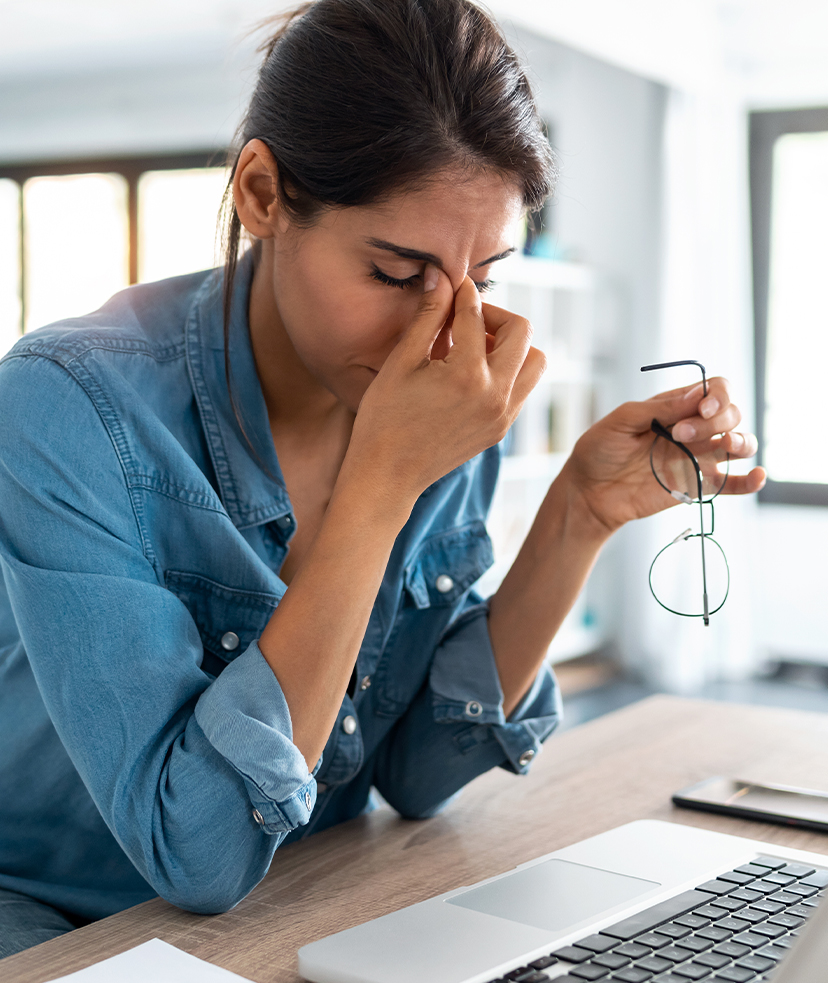 Photo of a stressed woman at work rubbing her eyes