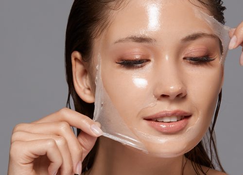 Photo of a woman peeling a chemical peel mask off of her face