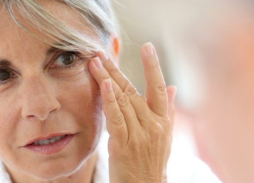 Photo of an older woman touching the wrinkles on her face