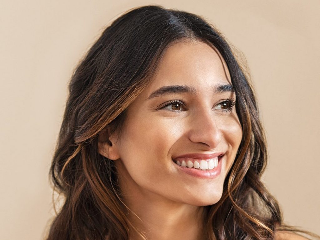 Photo of a smiling woman with dark hair against a beige background