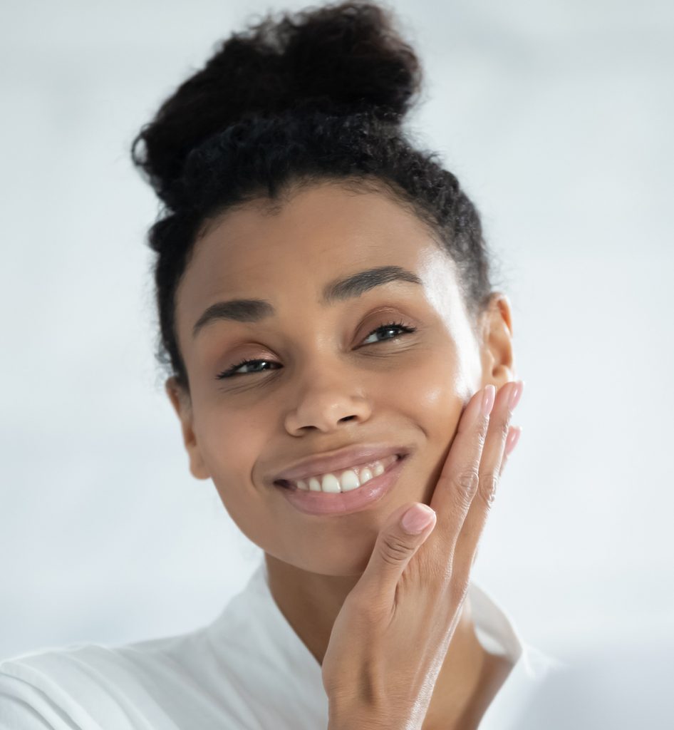 Photo of a young woman with great skin touching her face