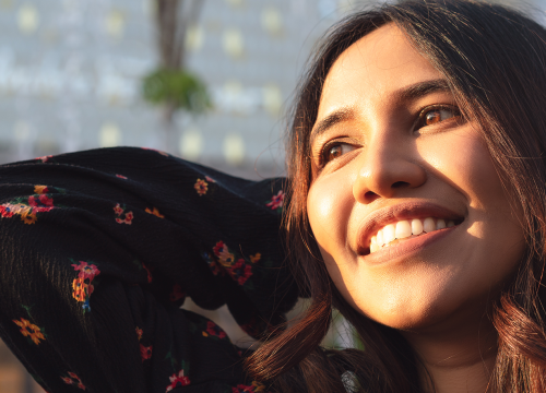 Photo of a smiling woman, standing in the sunshine