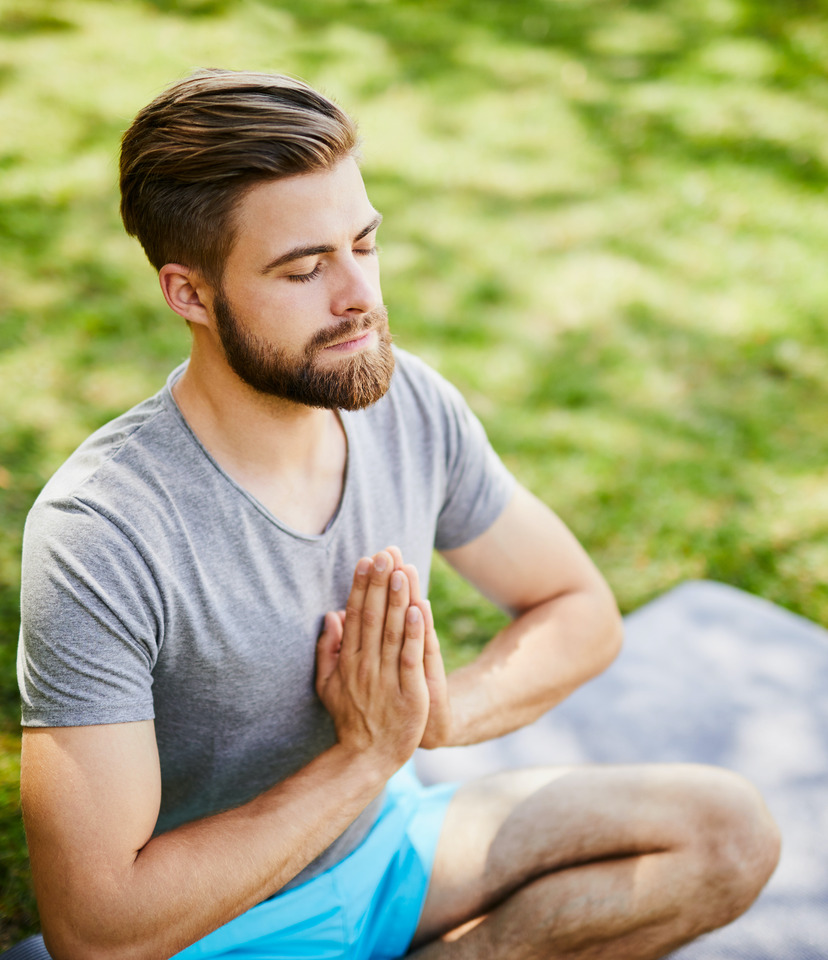 Photo of a man meditating on a yoga mat in the park