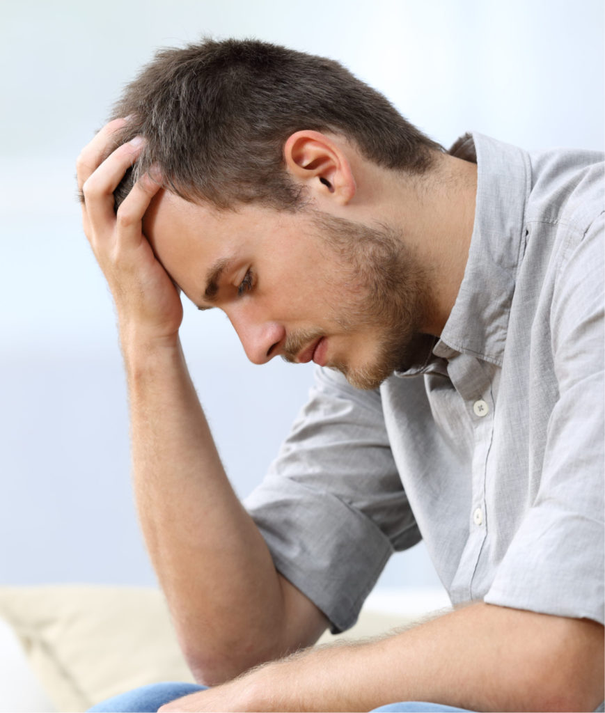 Man hunched over with his head on his forehead