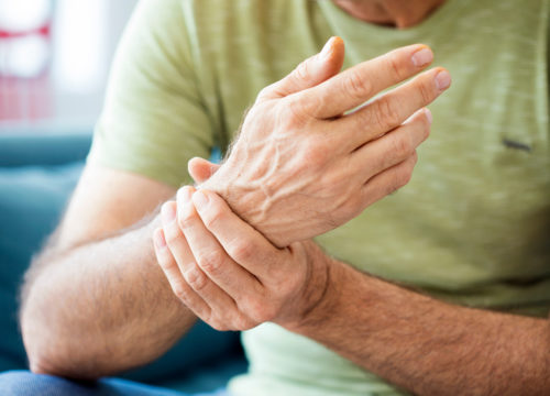 Elderly man grabbing his wrist