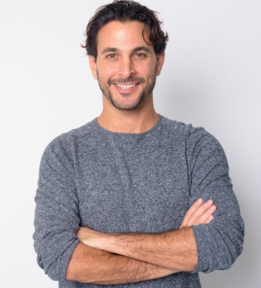 Photo of a smiling man wearing a gray sweater