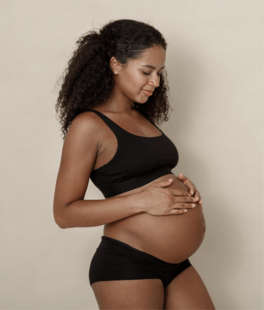 Photo of a pregnant woman resting her hands on her belly