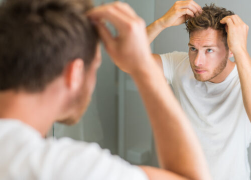 Photo of a man checking out his hair in the mirror